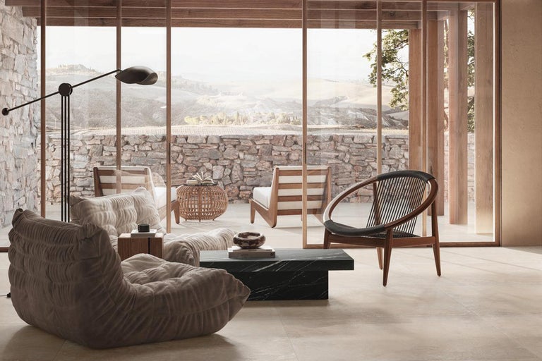 Cameră de zi luminoasă cu fereastră mare, fotoliu și perete din piatră naturală