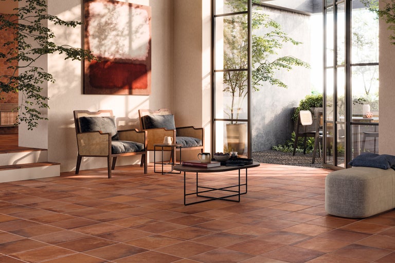 Living cu gresie de teracotă, fotolii din ratan și vedere spre grădină