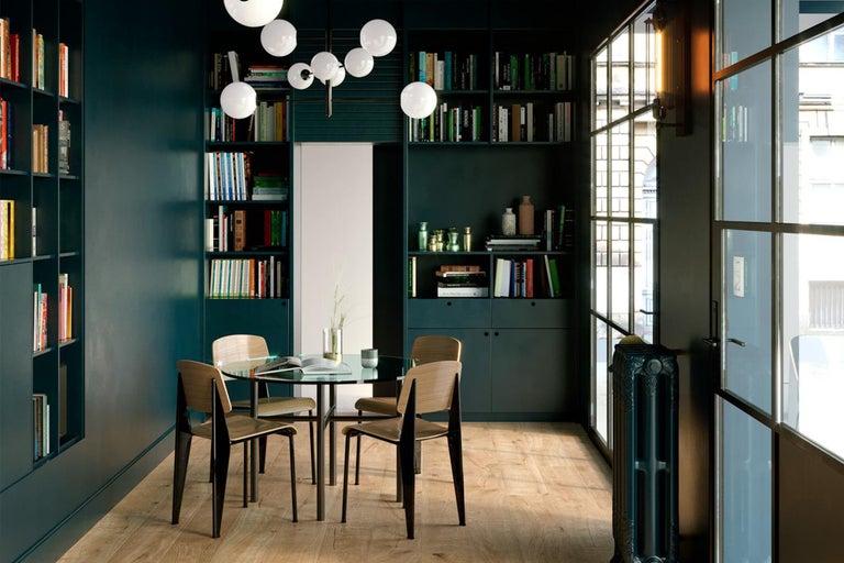 Sufragerie luminoasă cu biblioteci, masă rotundă de sticlă și scaune din lemn