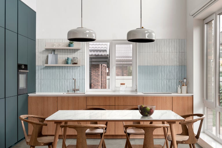 Bucătărie luminoasă cu masă de sufragerie, scaune, dulapuri de bucătărie și iluminat.