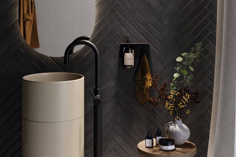 Baie modernă cu lavoar, robinet, oglindă și faianță închisă la culoare cu model herringbone.