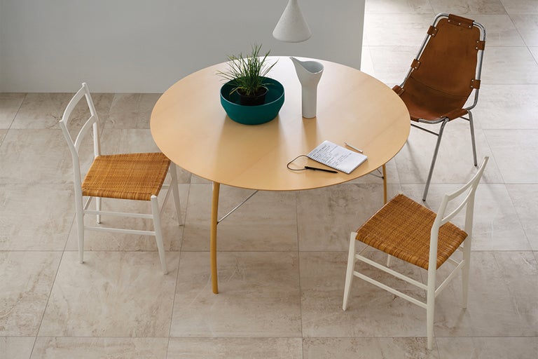 Scenă cu masă rotundă din lemn, scaune, plantă la ghiveci, blocnotes și ulcior