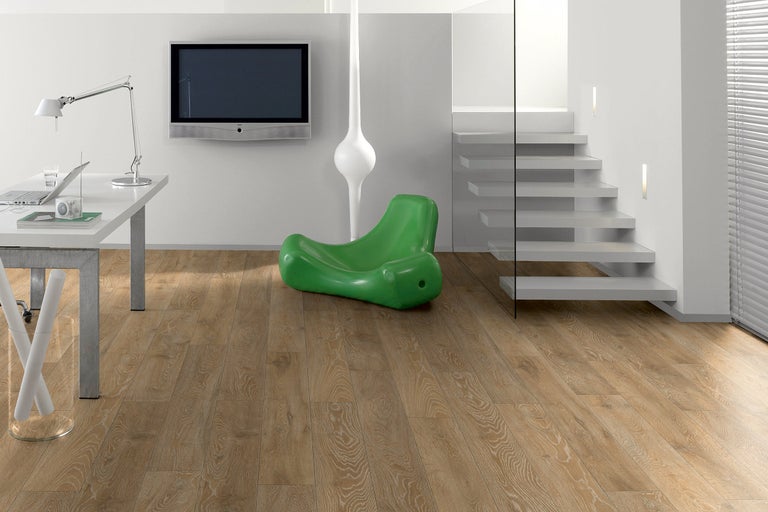 Cameră de zi luminoasă cu birou, televizor, scară și podea laminată.