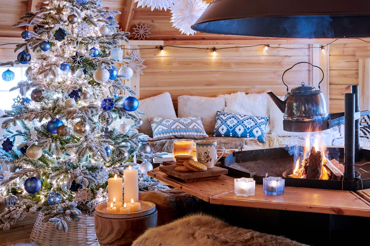 Scenă de Crăciun confortabilă cu pom împodobit, foc în șemineu și casă rustică din lemn