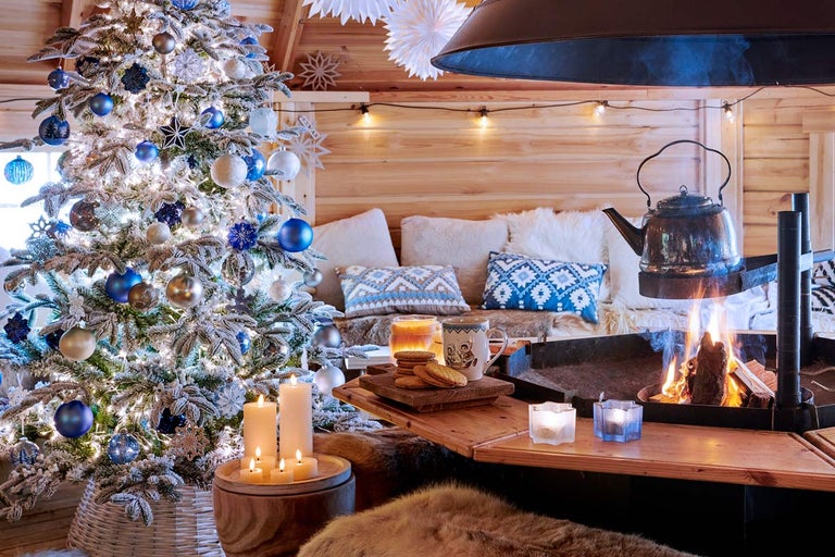 Scenă de Crăciun confortabilă cu pom împodobit, foc în șemineu și casă rustică din lemn