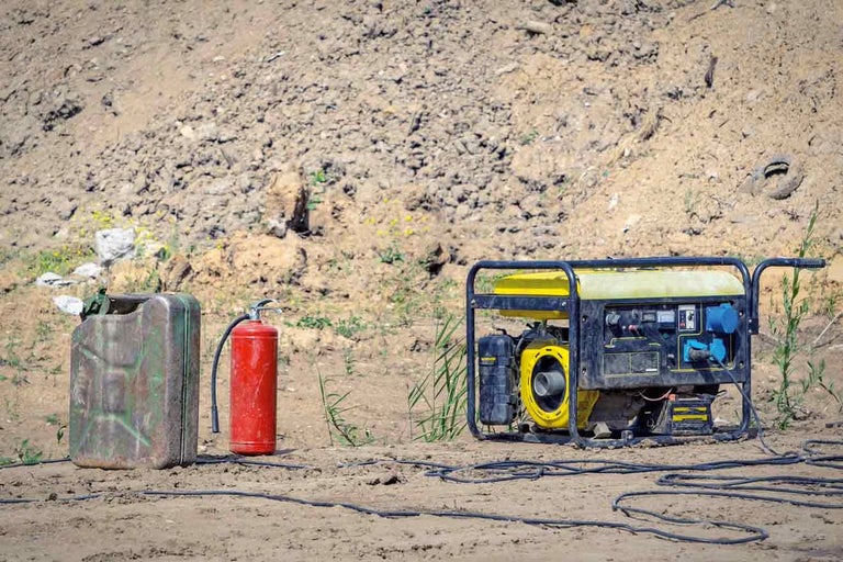 Generator de curent portabil cu bidon de combustibil și stingător de incendiu pe un șantier.