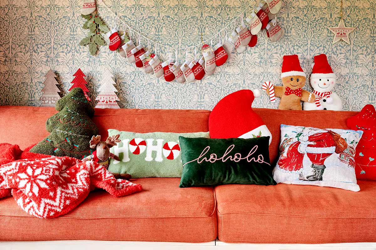 Cameră de zi decorativă cu motive de Crăciun pe o canapea portocalie.