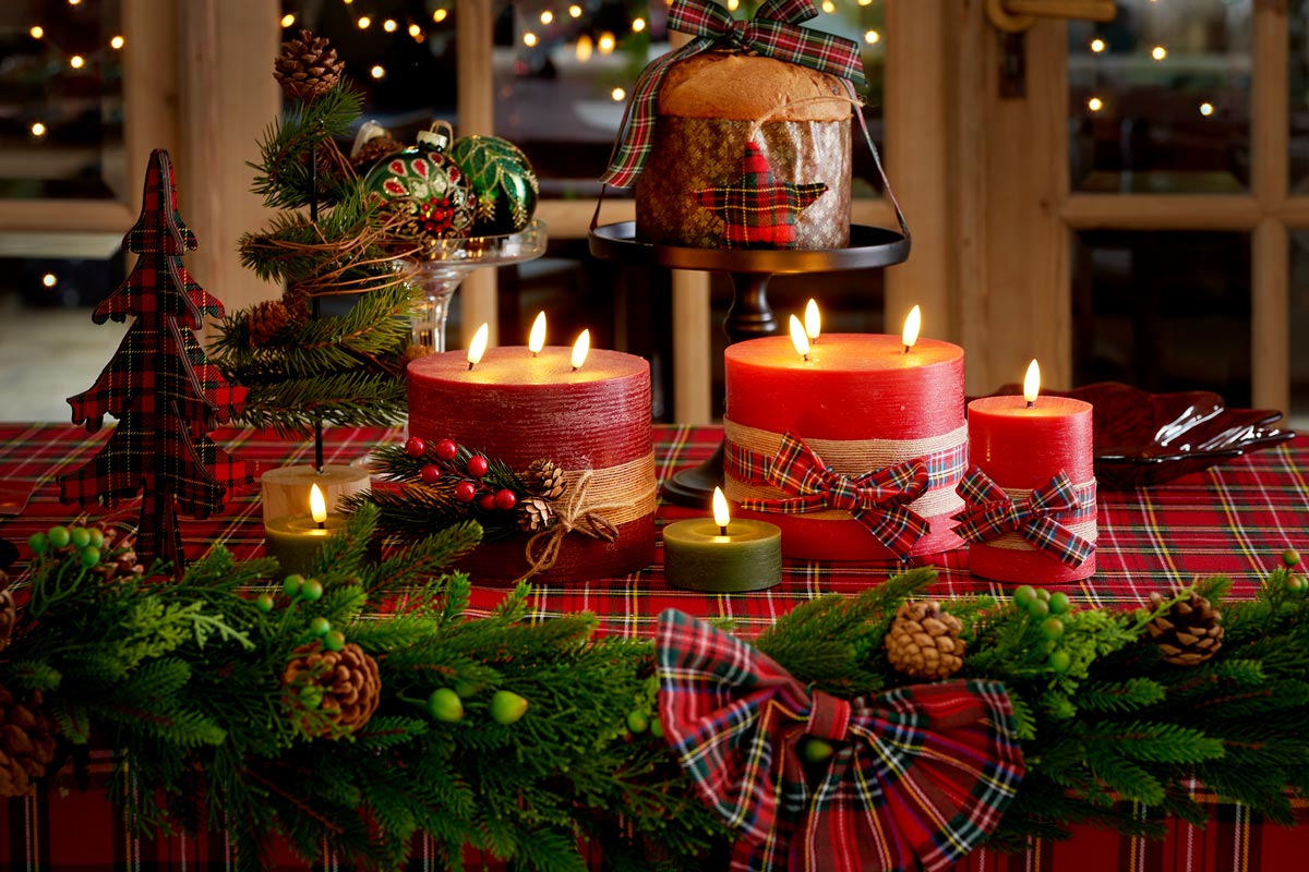 Masa aranjată festiv cu lumânări aprinse, verdeață de brad, decorațiuni și un panettone