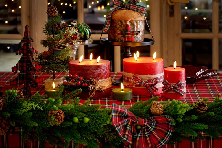 Masa aranjată festiv cu lumânări aprinse, verdeață de brad, decorațiuni și un panettone