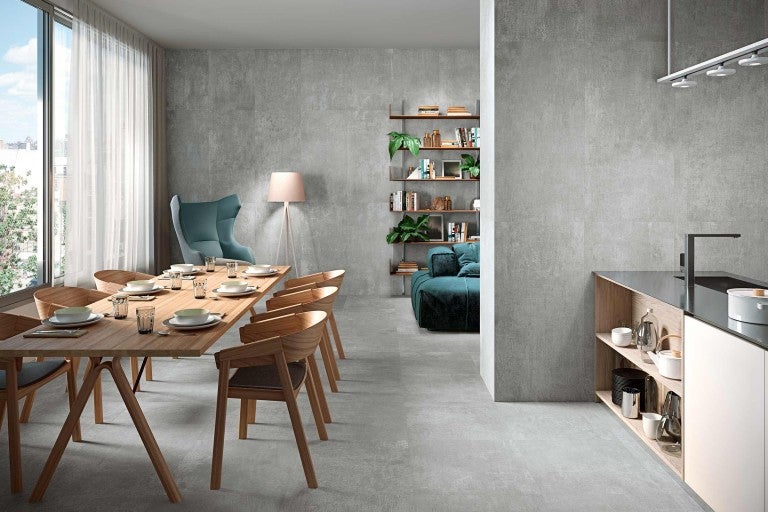 Cameră de zi luminoasă cu gresie aspect beton, masă de sufragerie și chicinetă