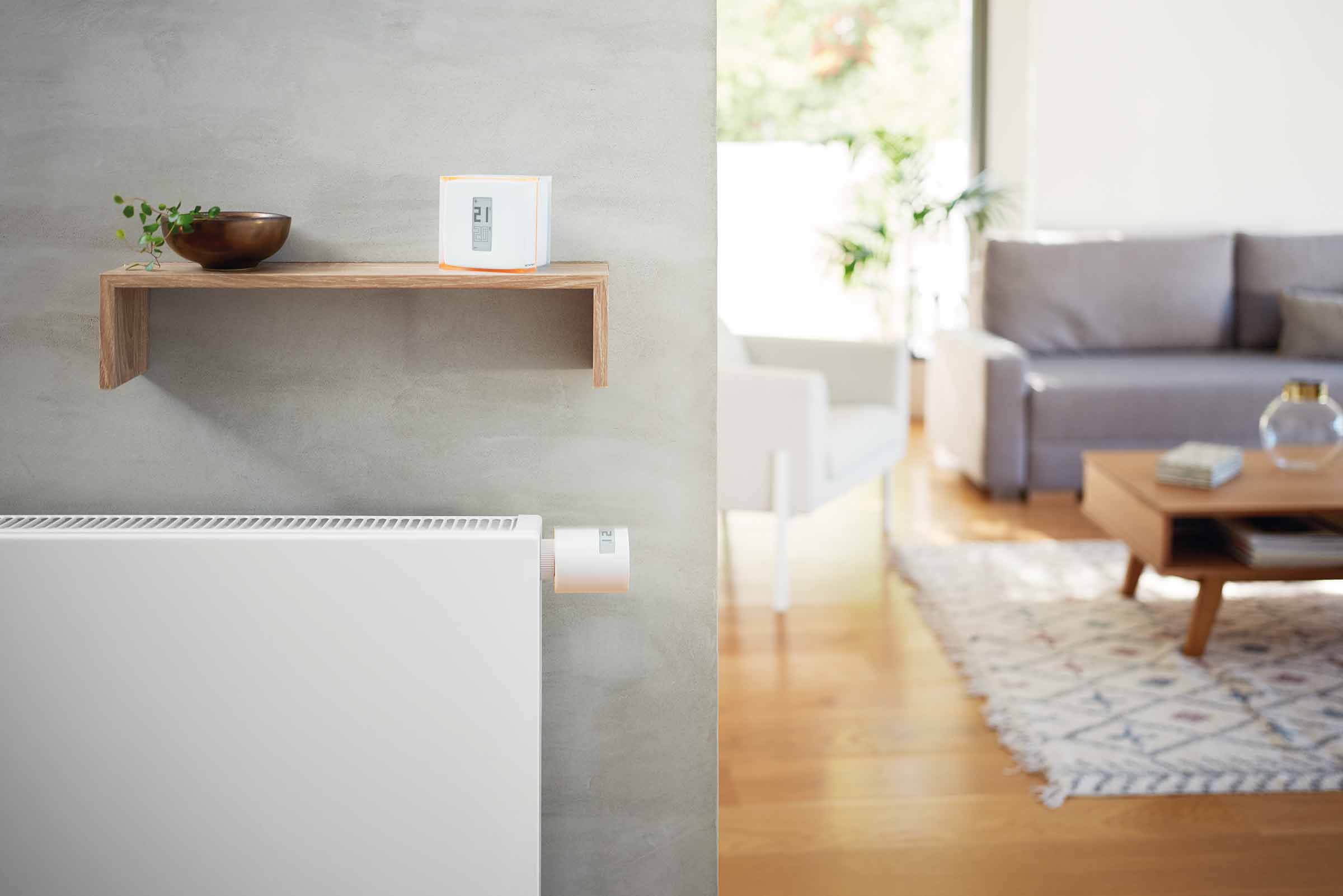 Cameră de zi luminoasă cu radiator, termostat și control smart home pe un raft
