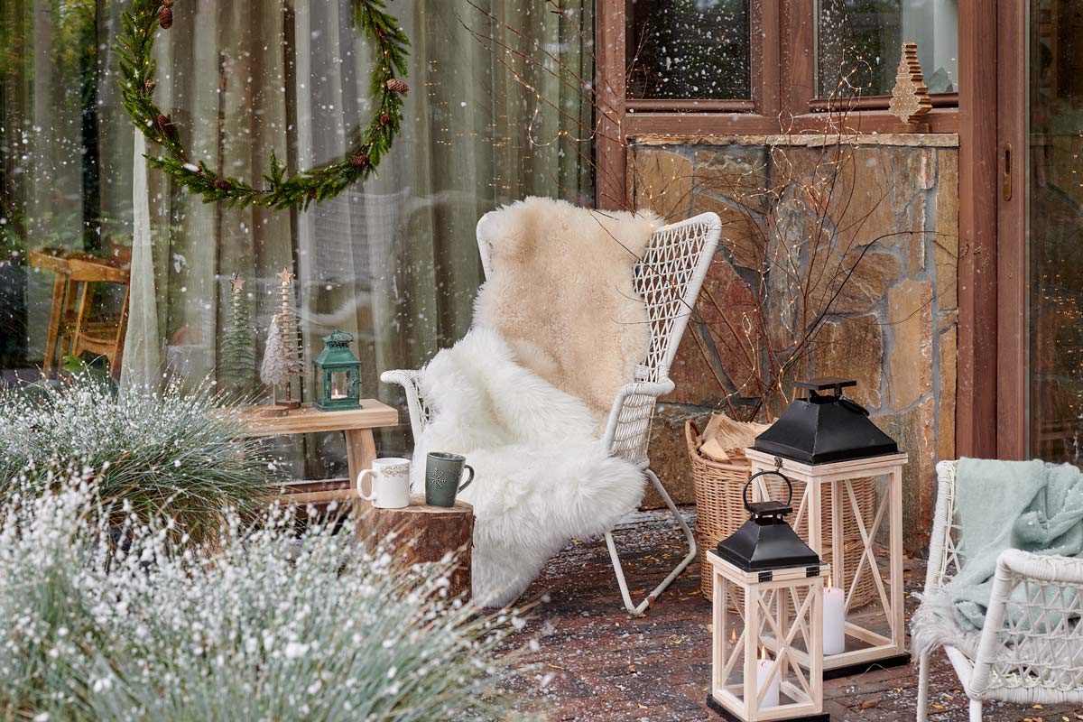 Decor de grădină de iarnă cu scaun, felinare și decorațiuni.