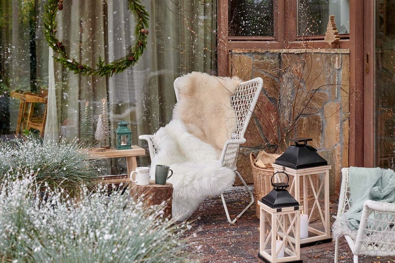 Decor de grădină de iarnă cu scaun, felinare și decorațiuni.