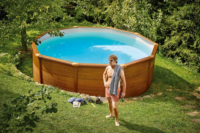 Piscină supraterană cu placare din lemn și persoană care face baie în grădină