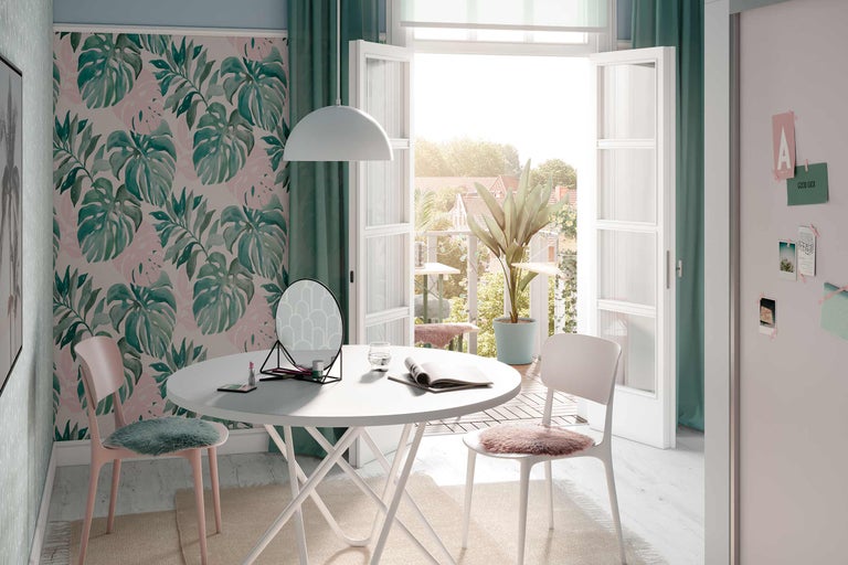 Cameră luminoasă cu tapet Monstera, masă albă, scaune, oglindă și decorațiuni pentru o atmosferă prietenoasă.