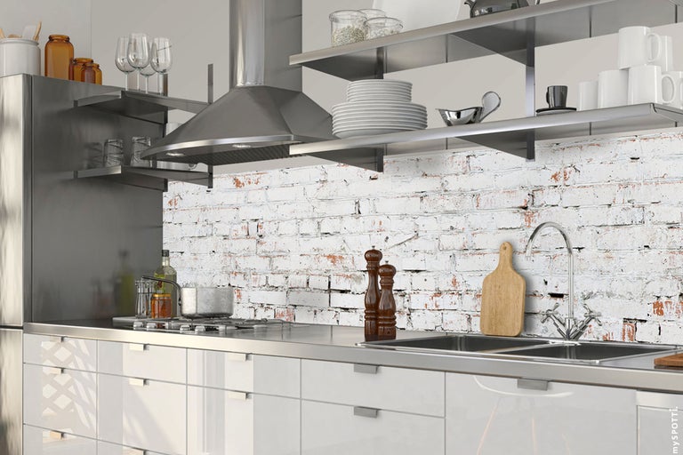 Bucătărie luminoasă cu dulapuri albe, chiuvetă din oțel inoxidabil, aragaz și hotă
