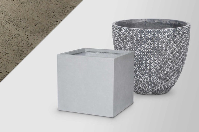 Două jardiniere din ciment: un ghiveci pătrat și un ghiveci rotund cu model