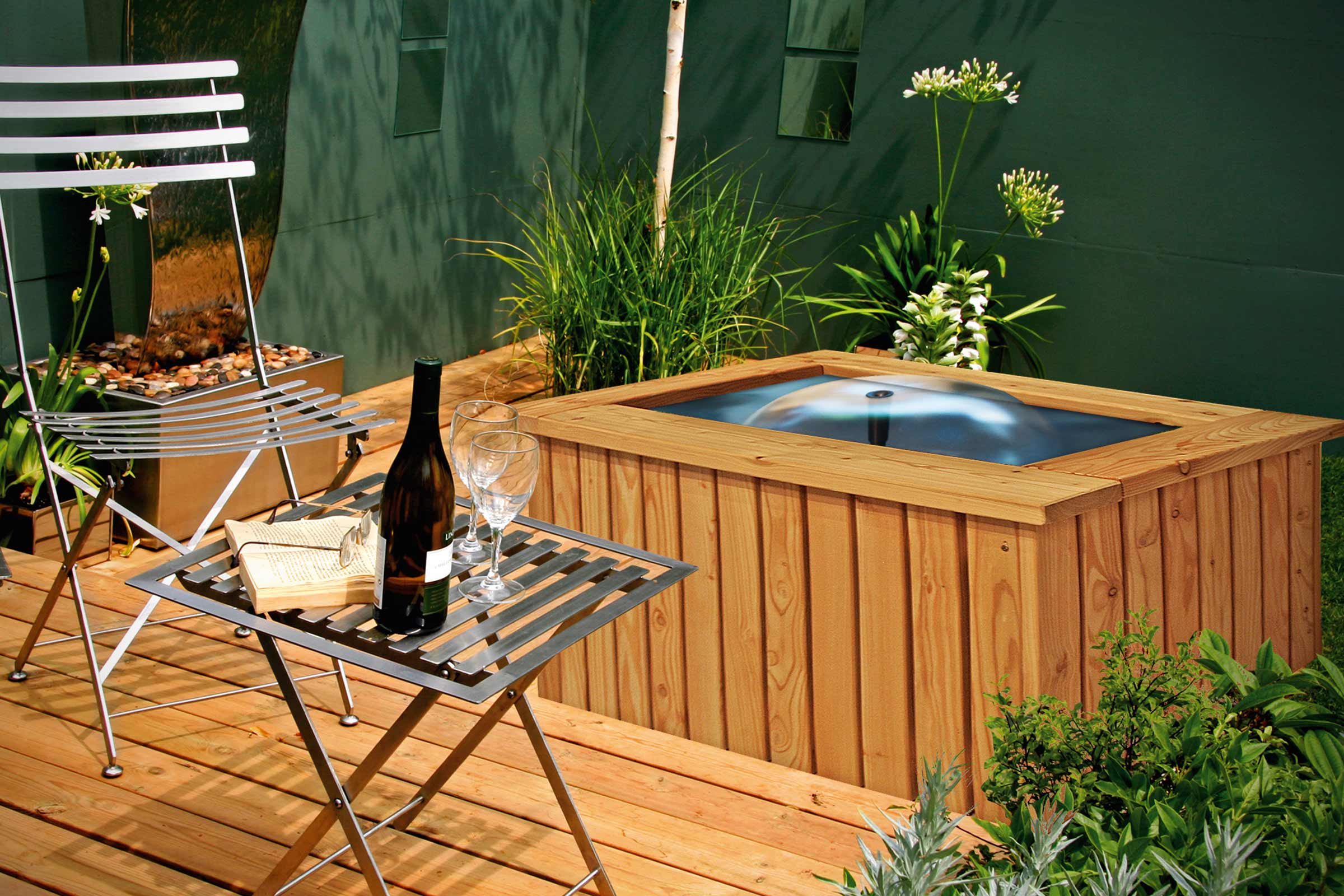 Scenă cu mobilier de grădină, cadă cu hidromasaj, sticlă de vin și pahare pe o terasă din lemn