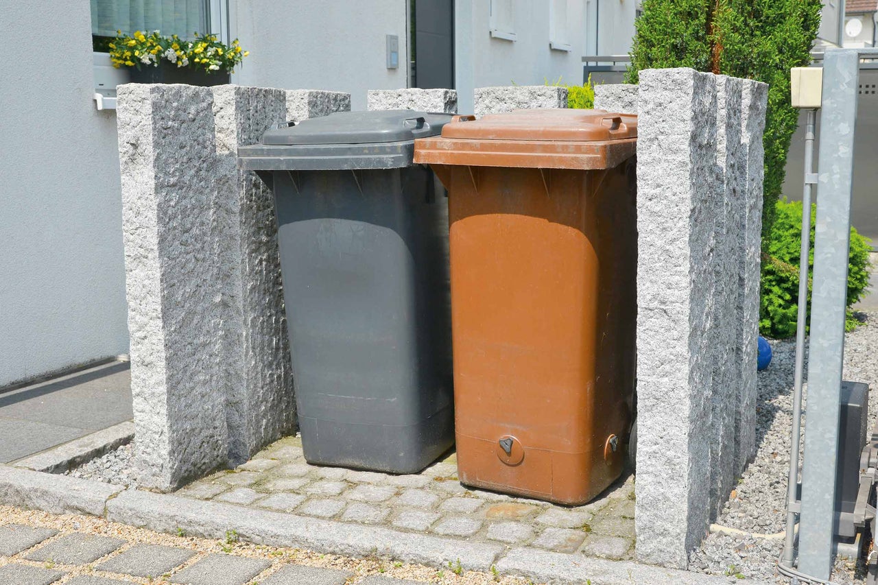 Două pubele într-un container de gunoi din piatră