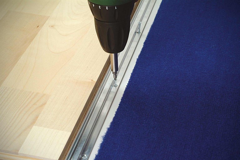 Montarea unei plinte pentru mochetă cu o șurubelniță cu acumulator pe o podea de lemn