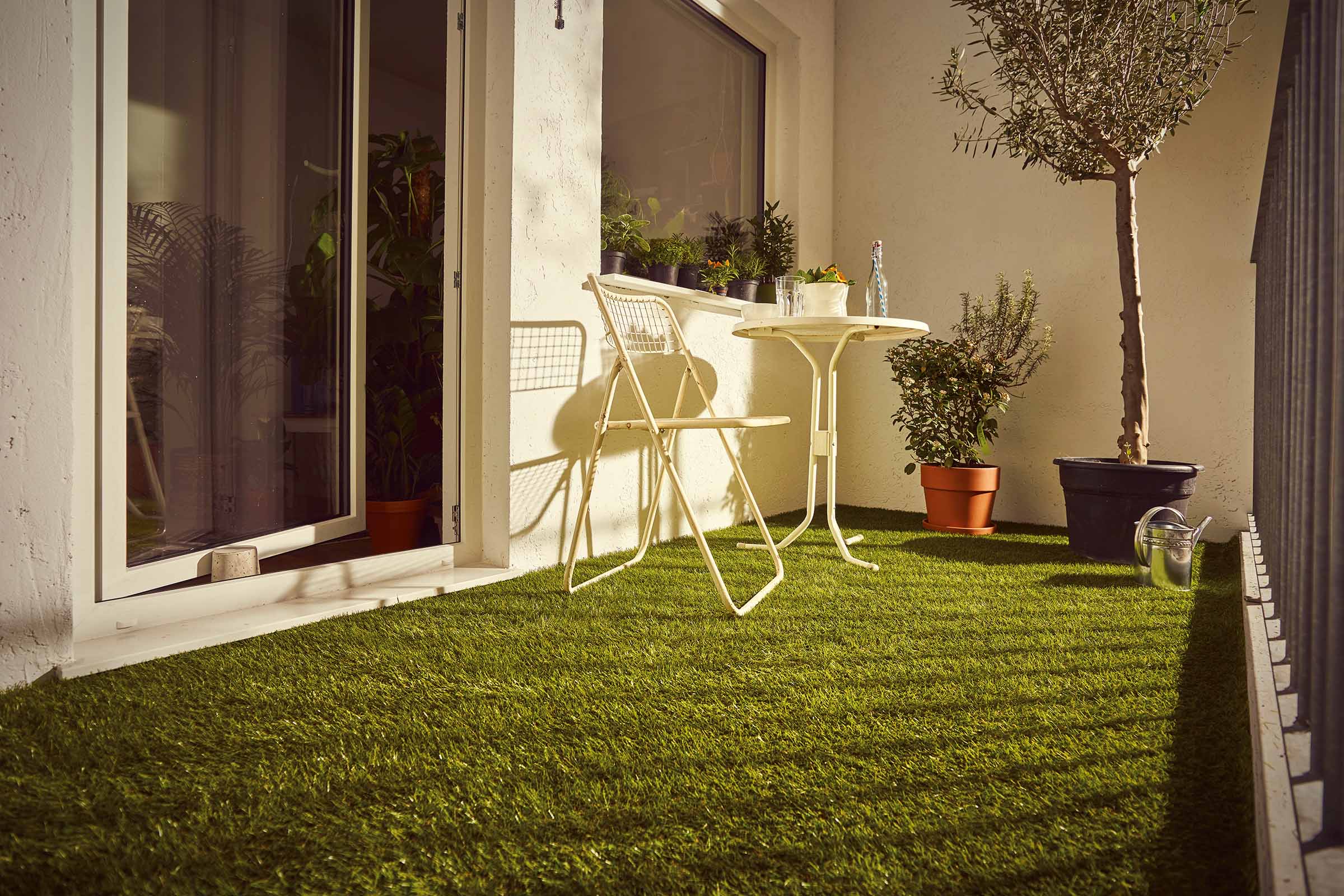 Balcon cu gazon artificial, scaun, masă și plante