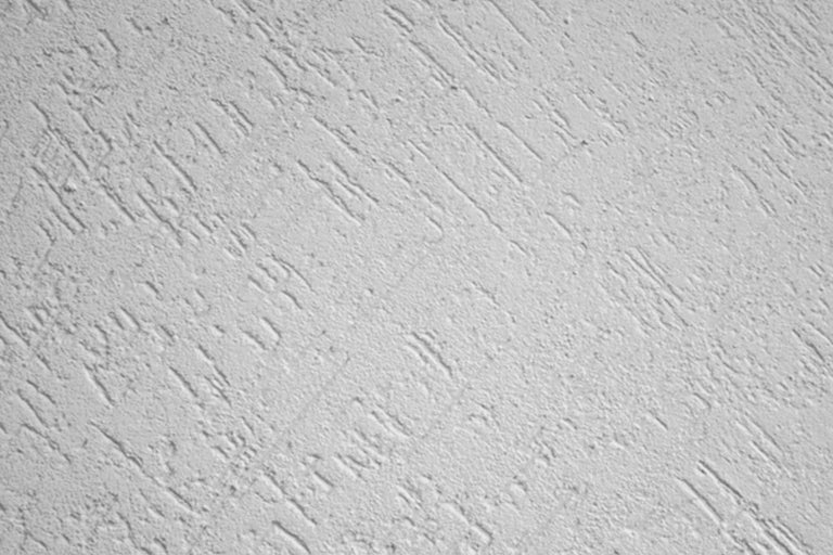 Imagine detaliată a unui perete cu o textură de tencuială zgâriată.