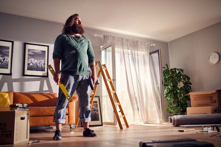 Cameră luminoasă în timpul renovării cu meșter, nivelă, scară și cutii de mutare