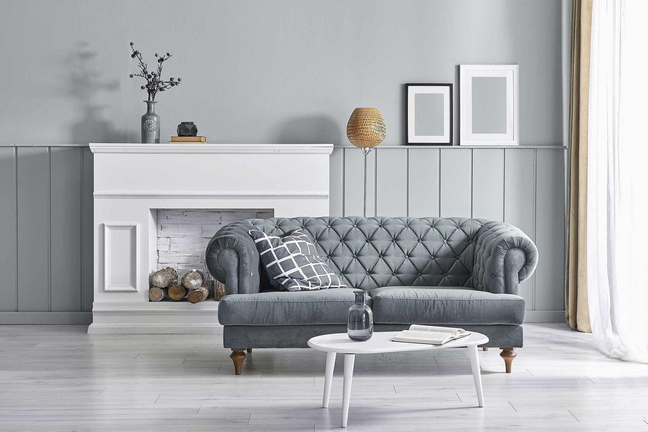 Scenă de living cu canapea gri, șemineu alb și masă rotundă