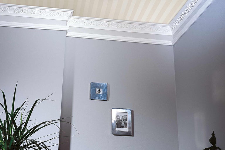 Colț de cameră cu muluri decorative pe perete și tavan