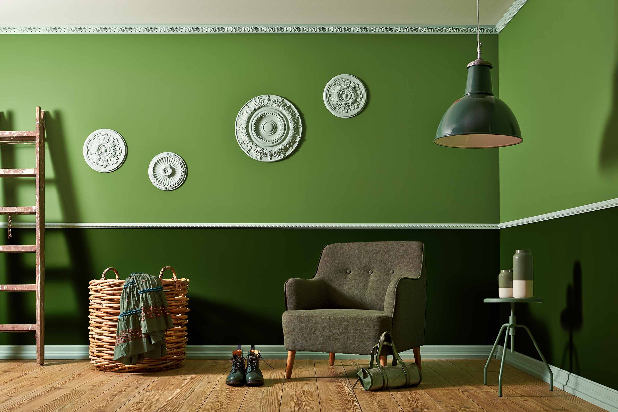 Cameră luminoasă cu pereți verzi, fotoliu, lampă și elemente decorative.