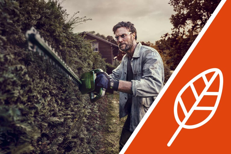 Bărbat tăind un gard viu cu o foarfecă de gard viu