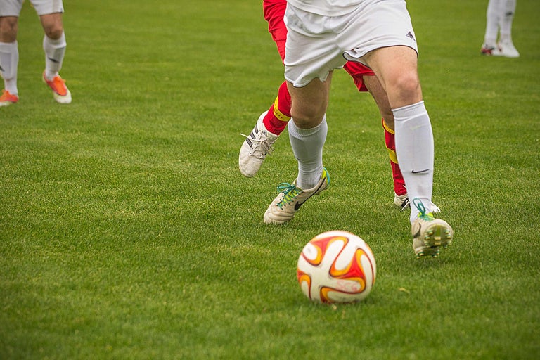 Jucători de fotbal pe un gazon verde cu o minge de fotbal