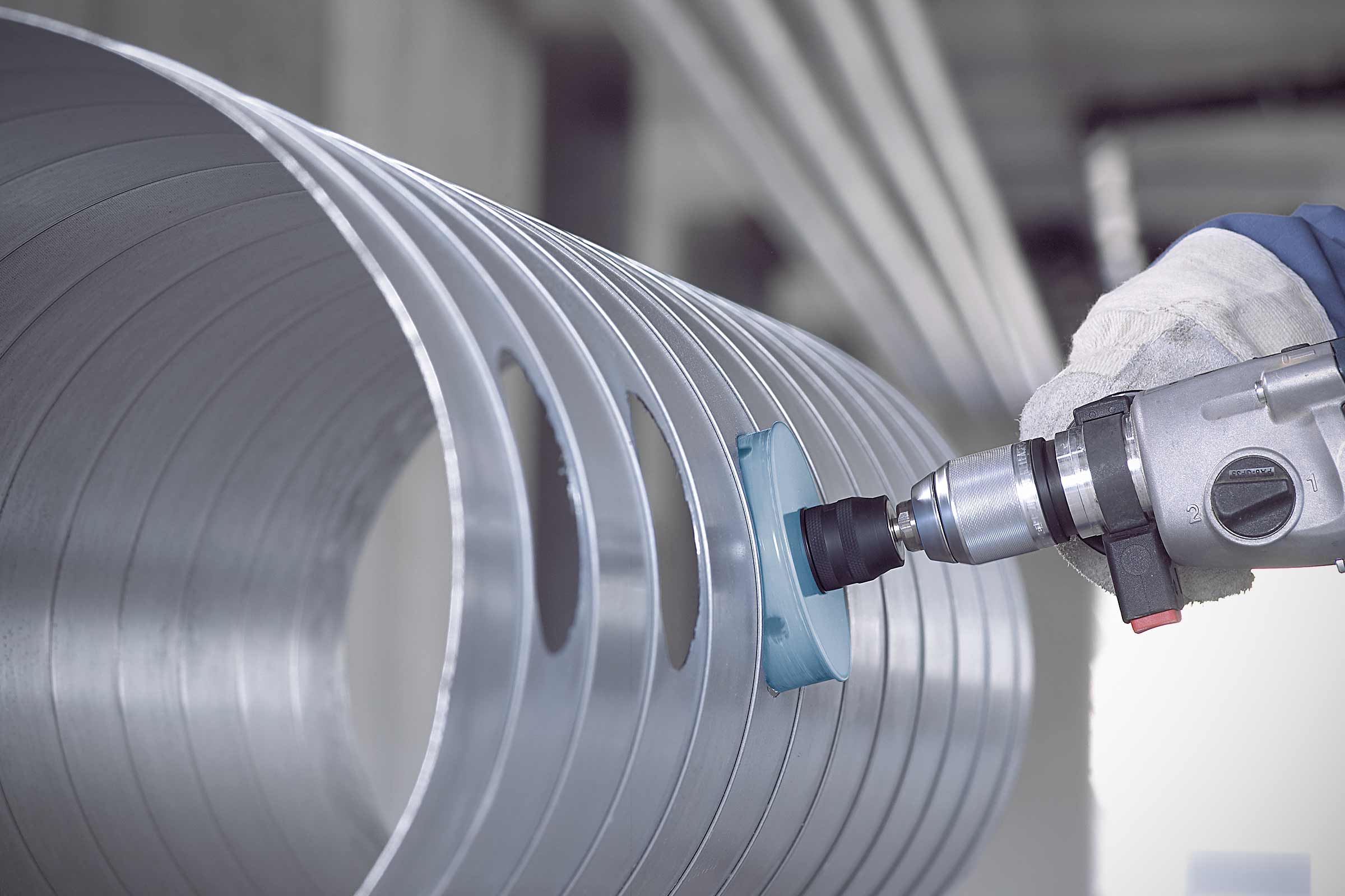 Unealtă de șlefuit pe o țeavă de aluminiu cu găuri, prelucrată cu o mașină de găurit