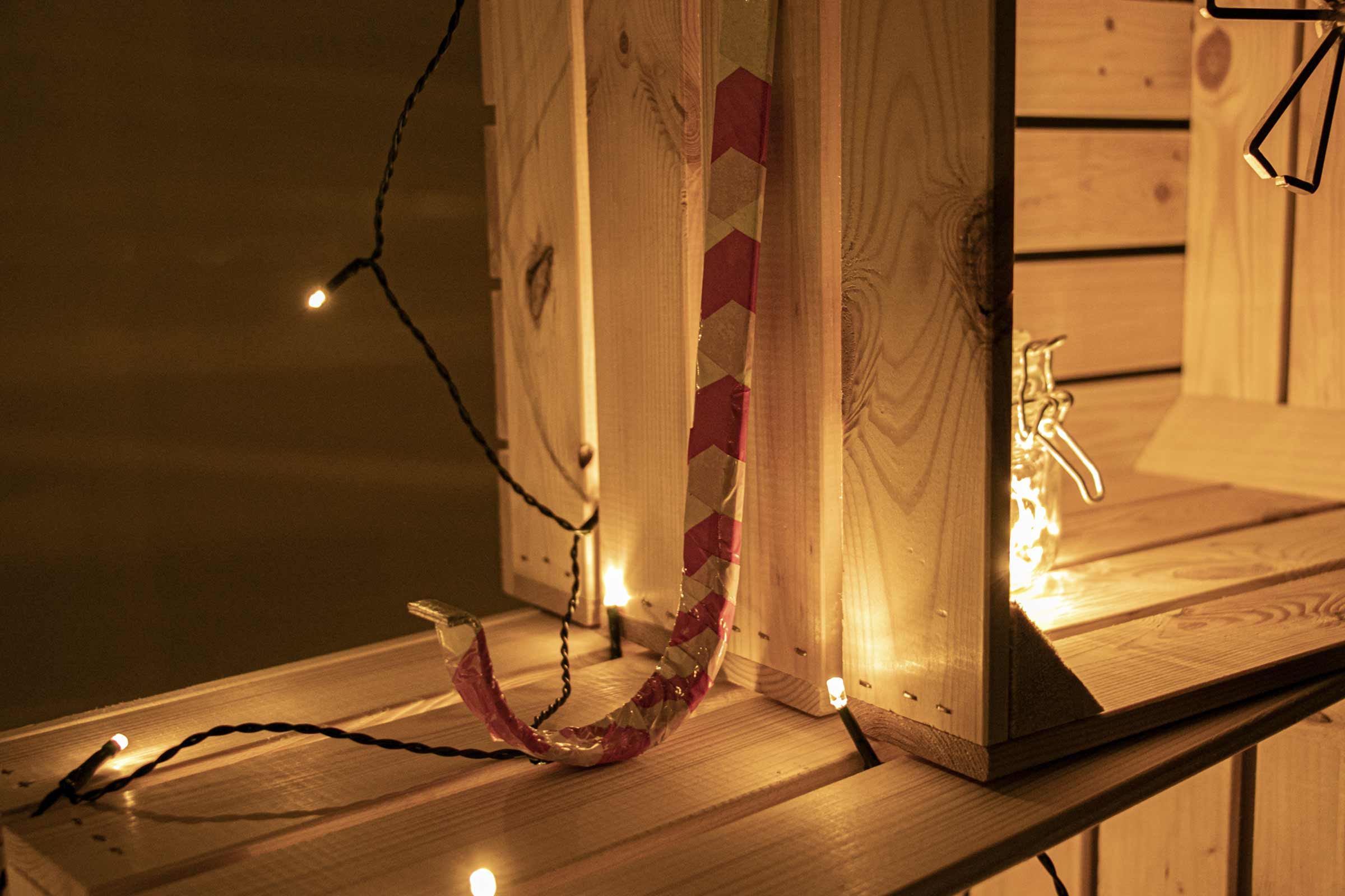 Raft din lemn cu decorațiuni, lanț luminos și un ornament cu model roșu