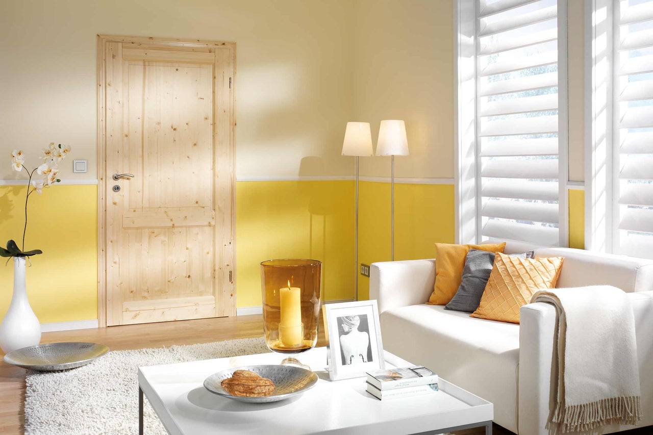 Amenajare interioară luminoasă cu ușă din lemn, canapea albă și jaluzele