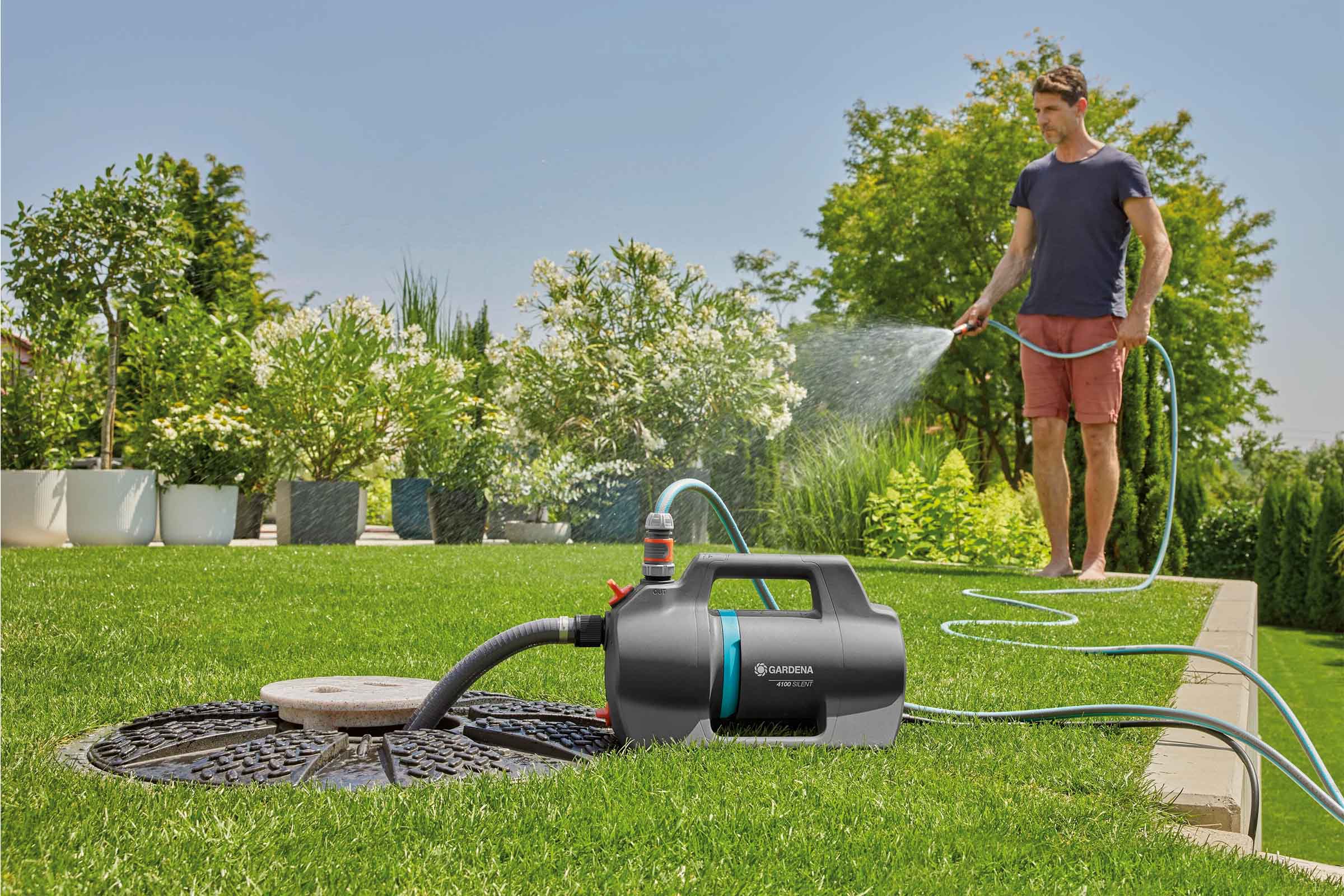 Scenă de grădină cu un bărbat udând plante cu o pompă de grădină Gardena