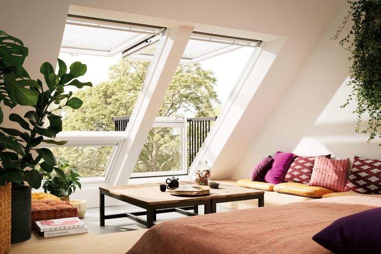 Cameră la mansardă cu două ferestre de mansardă deschise și balcon din lemn