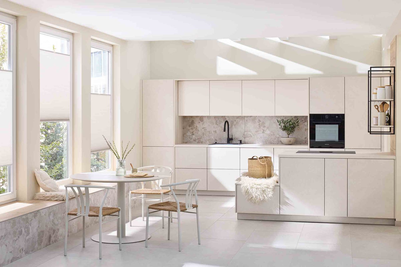 Bucătărie luminoasă cu masă, scaune și dulapuri încorporate, oferind o impresie organizată și spațioasă.