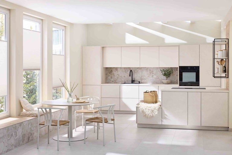 Bucătărie luminoasă cu masă, scaune și dulapuri încorporate, oferind o impresie organizată și spațioasă.