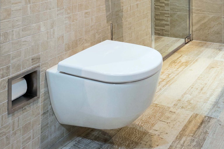 Baie modernă cu WC suspendat, placare cu faianță și suport de hârtie igienică încorporat