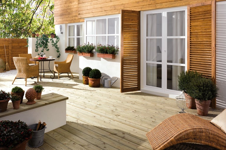 Spațiu exterior cu terasă din lemn, mobilier de grădină și plante