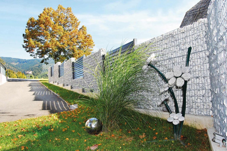 Gard gabion cu iarbă ornamentală și bilă metalică în grădină