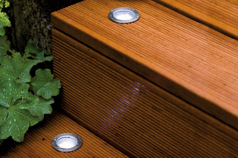 Prim-plan cu o scară din lemn cu lumini încorporate și plante