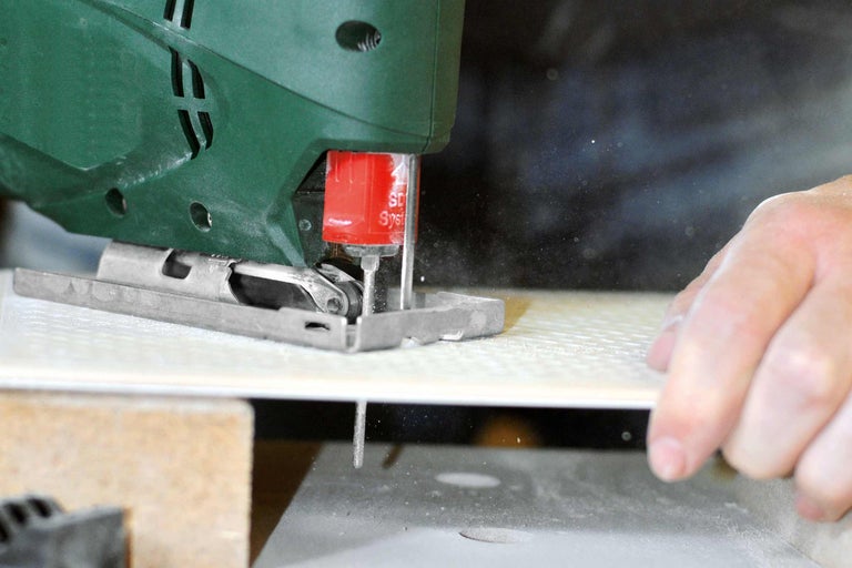 Prim-plan cu un ferăstrău vertical tăind o faianță