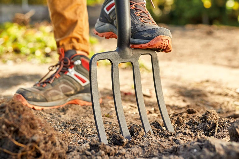 Persoană care împinge o furcă de săpat în pământ
