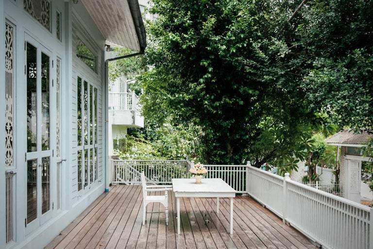 Verandă cu podea din lemn, masă, scaun și balustradă