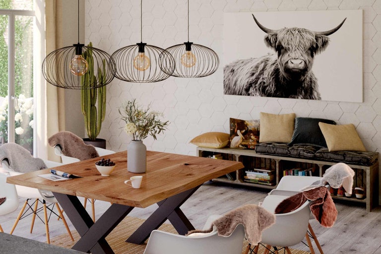 Sufragerie cu masă din lemn, lămpi suspendate și tablou cu vacă pe perete.