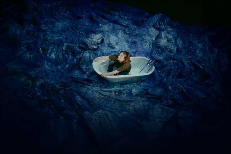 Femeie stând într-o cadă în mijlocul deșeurilor