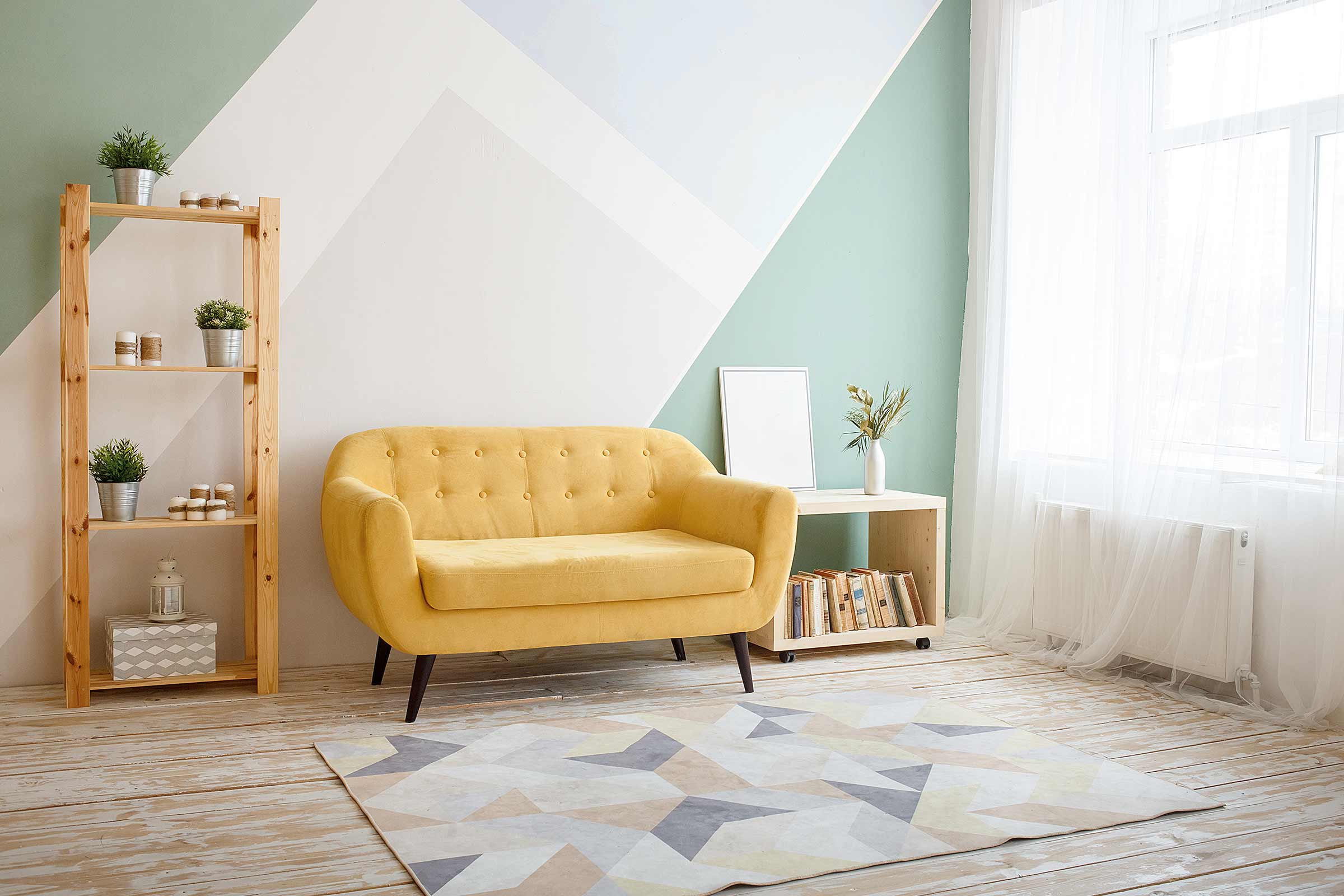 Living luminos cu canapea galbenă, raft din lemn și covor geometric