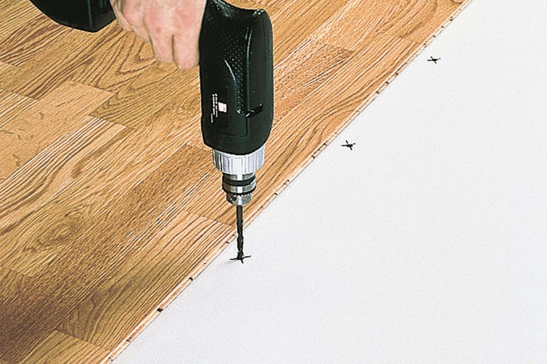 O mașină de găurit fixează panourile laminate pe un strat suport.